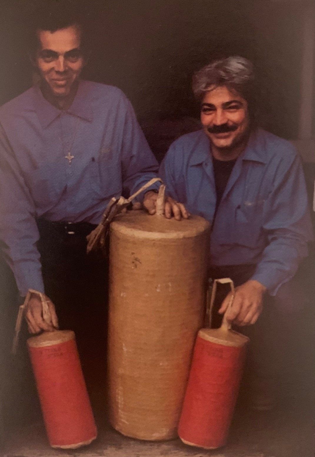 August and Nunzio Santore in blue shirts crouching beside a large wrapped shell and two red shells