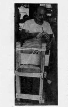 Charles Santore seated at a wooden frame tying fuse by hand, from a 1976 archival print