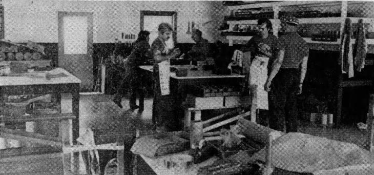 Three people working at benches across the factory floor in a 1983 newspaper print