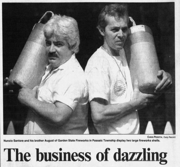Nunzio and August Santore back to back, each holding a large fireworks shell on a shoulder, in a news clipping
